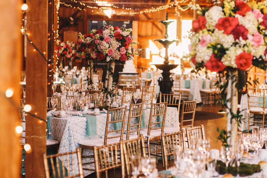 Rich dinner tables covered with blue clothes and sparkling glasswares stand in the wooden hangar; all items are charleston event rentals